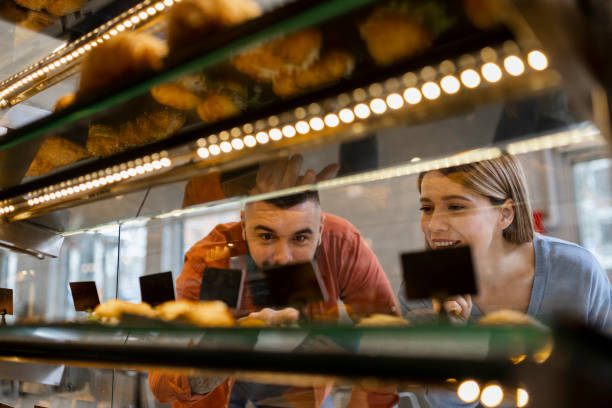 istock Beautiful young couple is choosing pastries and smiling while doing shopping at the bakery 2189758592