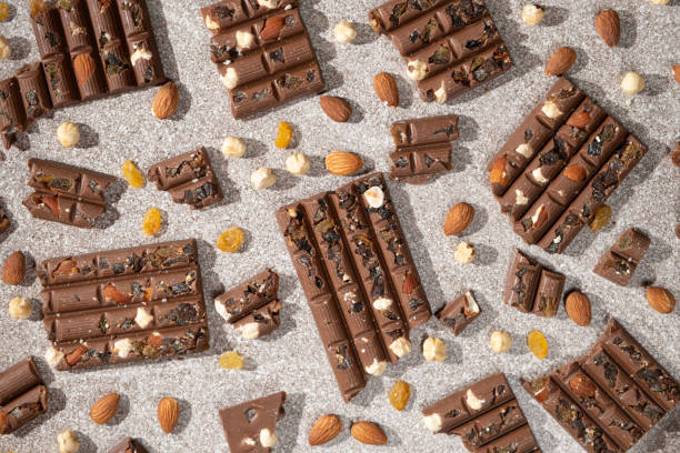 istock Broken chocolate pieces with nuts and raisins on a stone background top view 2189760943
