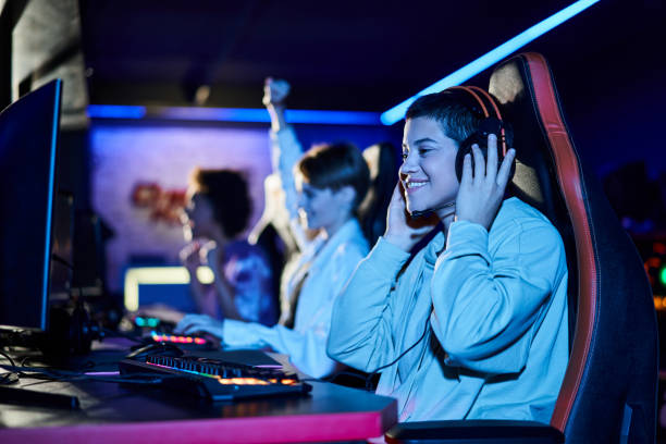 istock Young female friends enjoying gaming at a vibrant internet cafe with computers 2189762004
