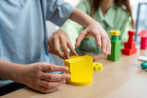 istock A caring babysitter helps a boy build colorful wooden blocks to promote learning. Develop small muscles and creativity 2189762625