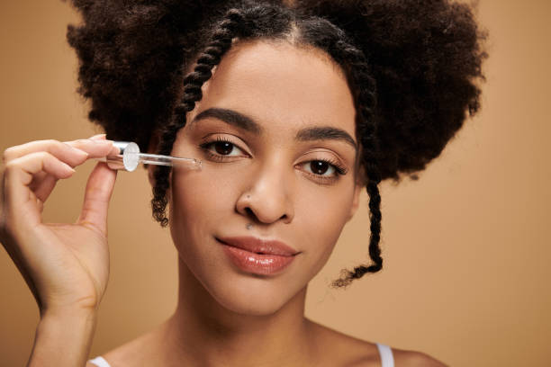 istock Young beautiful woman applying serum to her face with a joyful expression in a neutral setting 2189762627