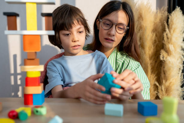 istock A caring babysitter helps a boy build colorful wooden blocks to promote learning. Develop small muscles and creativity 2189762639