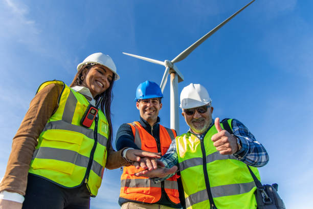 istock Engineers joining hands under wind turbine, promoting green energy 2189762658
