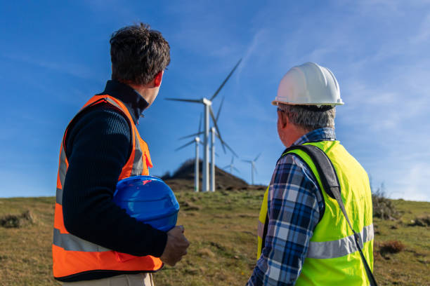 istock Engineers inspecting wind turbines in a field on a sunny day 2189762709