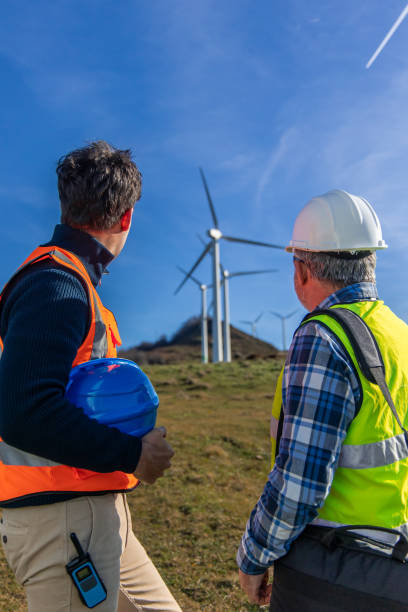 istock Engineers examining wind turbines in a field 2189762719
