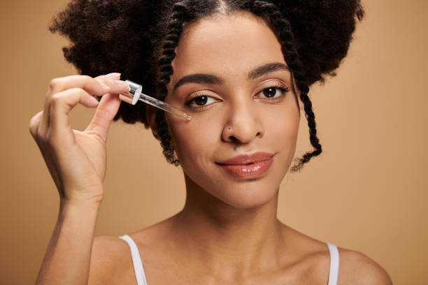 istock Young beautiful woman applying serum to her face in a warm toned setting 2189762732