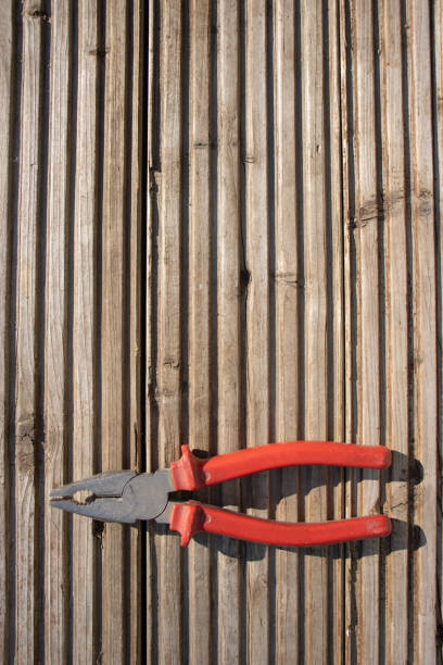 Red pliers on wooden background. Tools close-up. Carpentry. Repair and maintenance. Copy space, top view