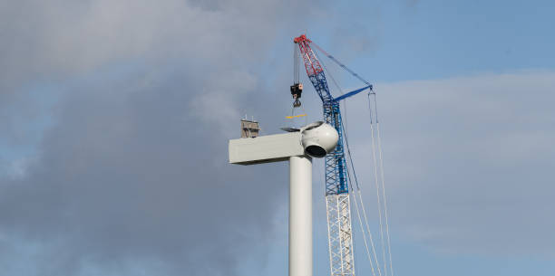 Crane lifts the nacelle onto a wind turbine tower during the construction of a wind farm