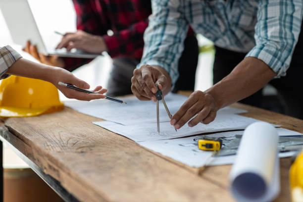 istock Brainstorming group of architects and engineers discuss building blueprint design paperwork and drawing construction project planning on wooden table in office. 2189771502