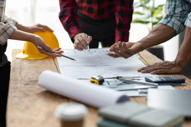 istock Brainstorming group of architects and engineers discuss building blueprint design paperwork and drawing construction project planning on wooden table in office. 2189771507