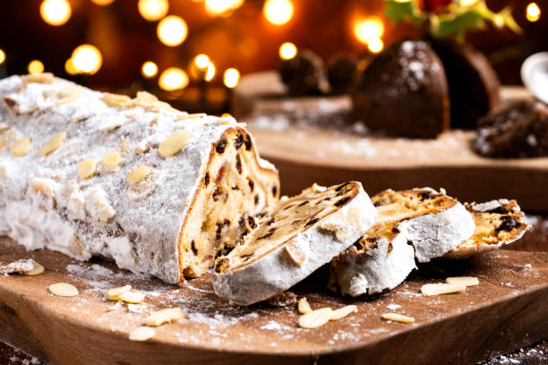 Sliced German Christmas fruit cake known as Stollen cake with bokeh background and Christmas decoration around the fruit cake.