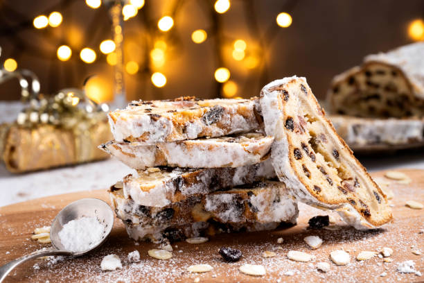 Sliced German Christmas fruit cake known as Stollen cake with bokeh background and Christmas decoration around the fruit cake.