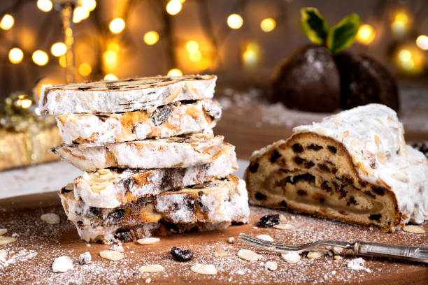 Sliced German Christmas fruit cake known as Stollen cake with bokeh background and Christmas decoration around the fruit cake.