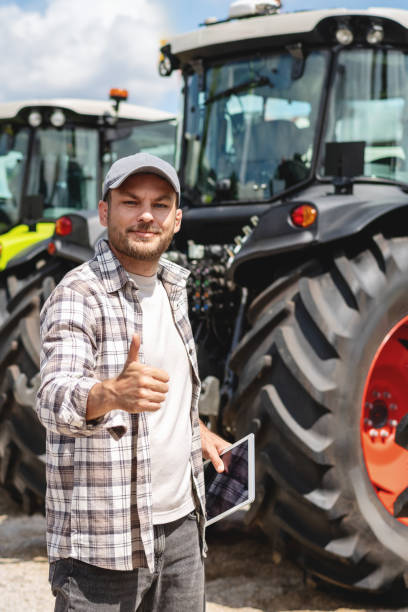 istock Man standing next to farm tractors and gestures thumb up. 2189779110