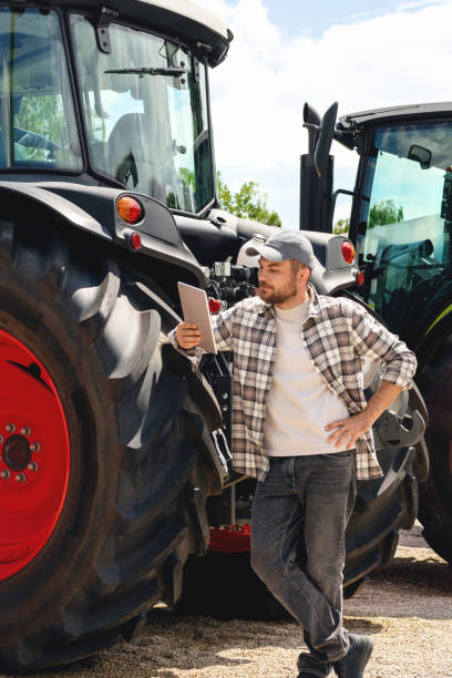 istock Caucasian man stands next to tractors and using digital tablet. 2189779137