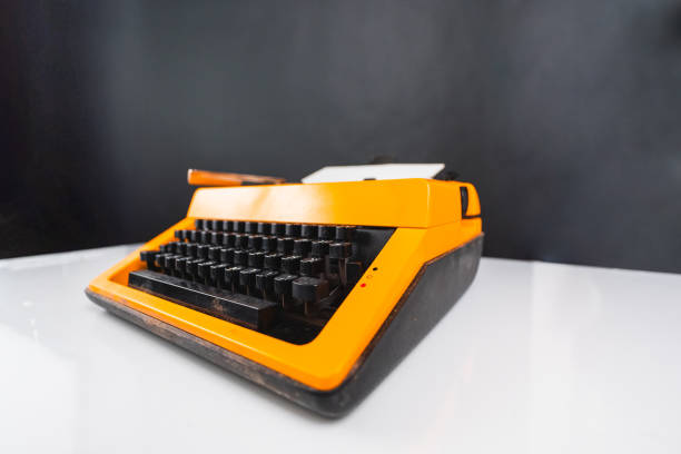 An artistic photo of a classic yellow typewriter sitting on a white desk, highlighting its retro design, set against a dark backdrop, perfect for concepts of creativity and nostalgia.