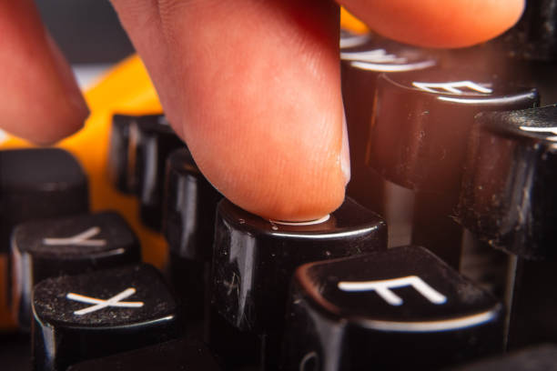 Macro photograph focusing on a finger pressing a raised black key, emphasizing texture and design. The background complements the retro aesthetic, showcasing interaction with vintage technology