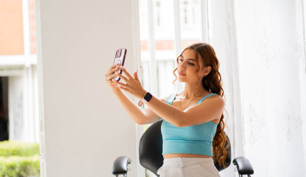 istock young woman sitting taking a selfie at home 2189780950