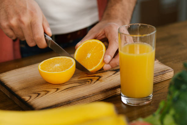 istock Close up of man's hands cutting an orange and making juice 2189783349
