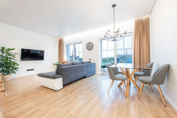 istock Modern Home Living Room Interior with Glass Dining Table and Large Windows. TV Screen, Sofa, Couch and Stairs in Background. 2189783570