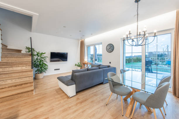 istock Modern Home Living Room Interior with Glass Dining Table and Large Windows. TV Screen, Sofa, Couch and Stairs in Background. 2189784254