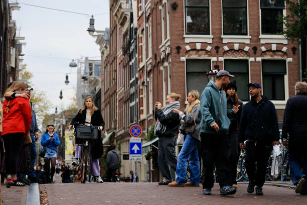 Tourists are making photos while people are walking around in the streets of Amsterdam.