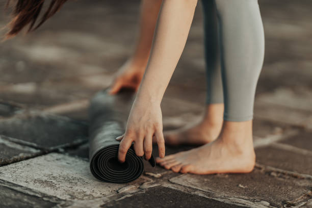 istock Woman Rolling Up Yoga Mat And Preparing To Outdoors Training 2189788130