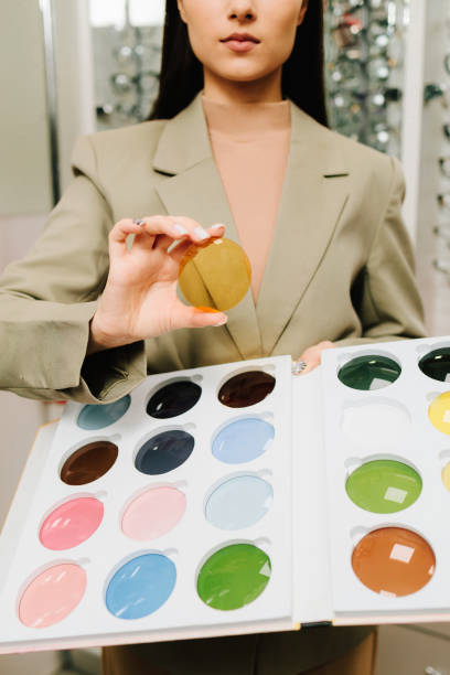 istock Selecting eye lens after optic checkup. Large selection of colorful lenses for eyesight correction. Female client holds colorful optical lens in the optical store. 2189794667