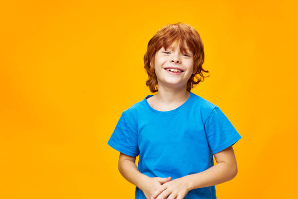 istock Happy red-haired boy smiling at the camera on a yellow background 2189797526