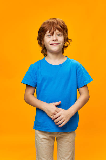 istock smiling redhead boy front view blue t-shirt yellow background 2189798406