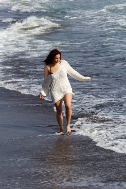 istock Hispanic Woman Walking On Beach With Ocean Waves 2189800650