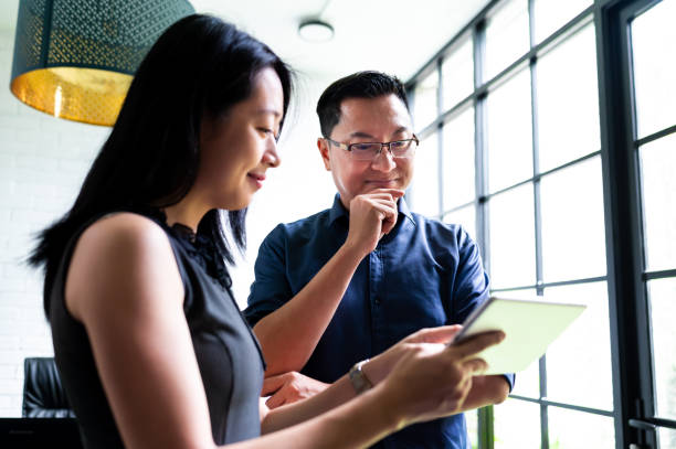 istock Two Asian entrepreneurs with a digital tablet and stand next to the office window 2189810240