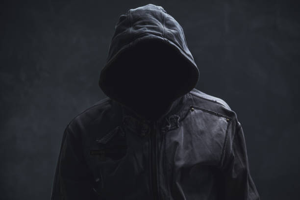 istock Unrecognizable cyber criminal or computer hacker wearing black hooded jacket, low key portrait 2189816363