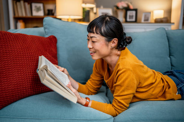istock Woman reading a book on the sofa at home 2189820050