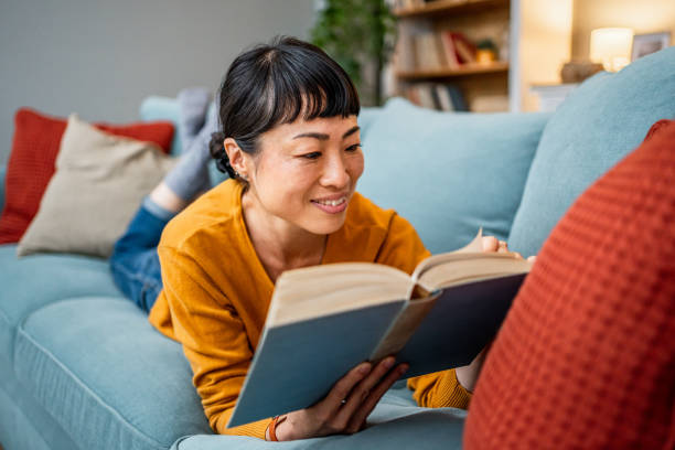 istock Woman reading a book on the sofa at home 2189820678