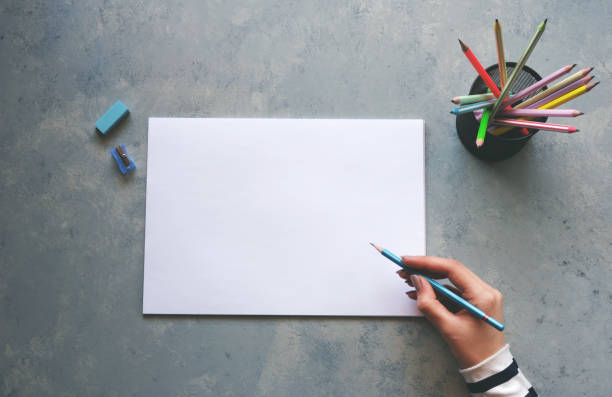 istock Woman writing on a blank white paper on a gray table 2189825252