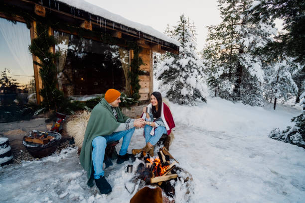 istock Couple with dog siting around fire pit in front of the cabin 2189827247