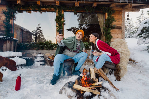 istock Couple with dog siting around fire pit in front of the cabin 2189827254