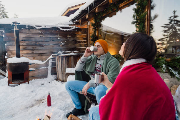 istock Couple with dog siting around fire pit in front of the cabin 2189827257