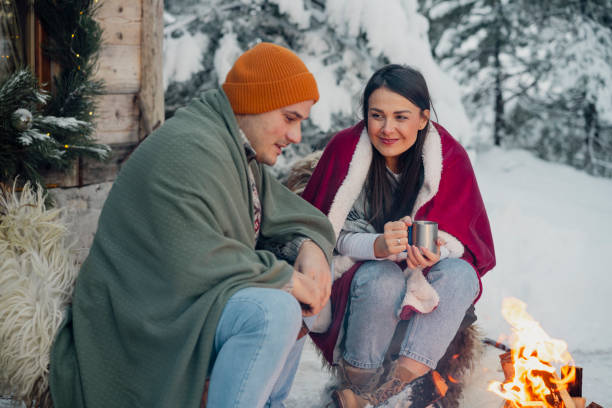 istock Couple with dog siting around fire pit in front of the cabin 2189827421