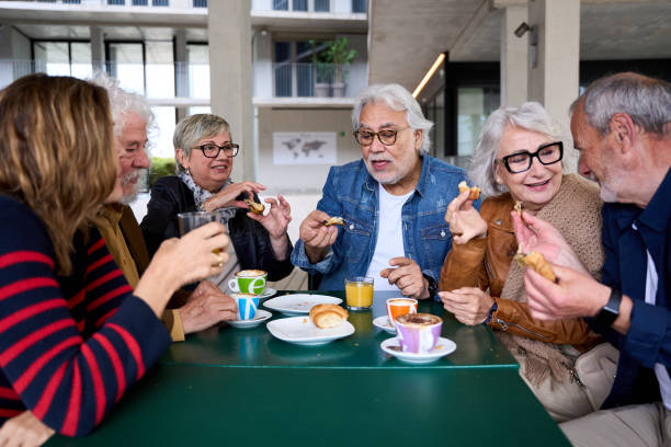 istock Group happy elderly friends gathered on cafeteria terrace eating and drinking coffees and pastries. 2189833031