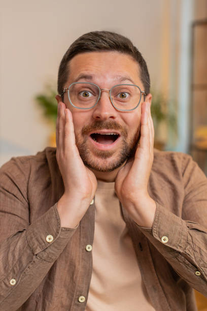 istock Caucasian young man guy looking at camera shocked by sudden victory sitting at home office table 2189836485