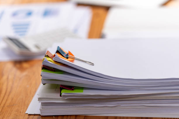 istock Paper documents are stacked on wooden desks at the workplace. 2189840098
