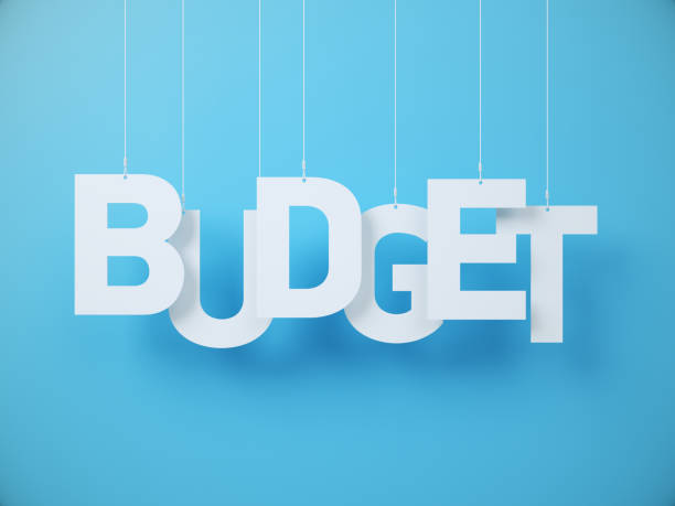 istock Budget Wording cut on white note paper hanging on string, White note paper on a blue Background. 2189849825