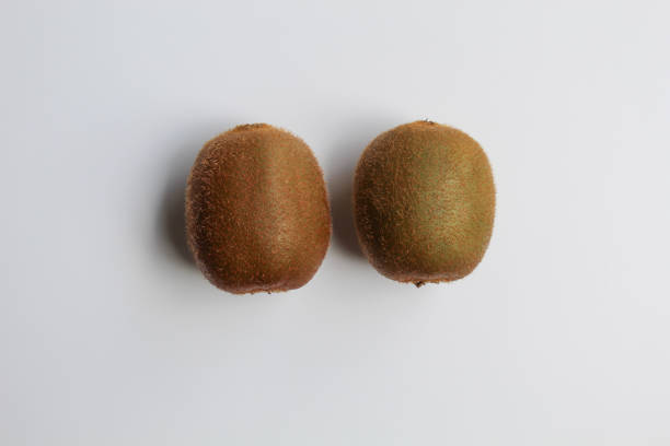 Two uncut kiwi fruits isolated on white background, flat lay or top view