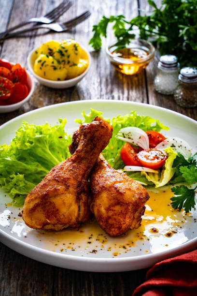 istock Barbecued chicken drumsticks with fresh vegetables on wooden table 2189870914