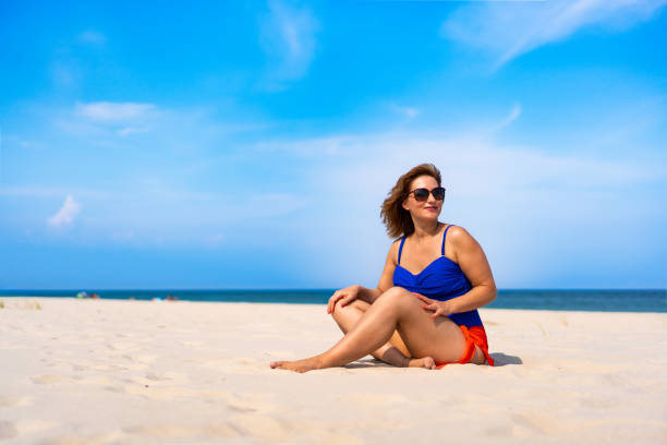 istock Beautiful mature woman sitting on sandy beach 2189873058