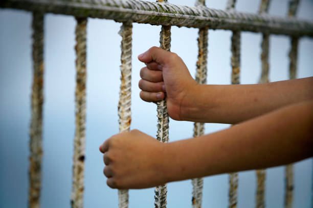 istock Child's Hands Grasping Rusty Metal Bars at the Seaside 2189874837