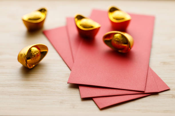 Red envelope and golden ingot or Yuanbao on wooden background for celebration happy Lunar New Year or Chinese New Year. Selective Focus.
