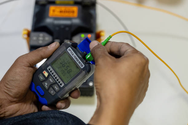 Optical fiber installation with Digital Fiber Optical Fusion Splicing machine. High precision fiber optic cleaver is being used during a fiber optic wire install at House. Welding of optical fibers.